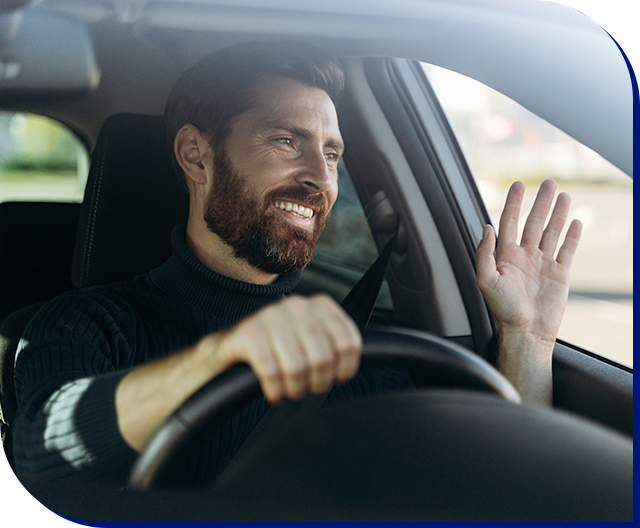 Motorista sorrindo ao volante, com a mão levantada em cumprimento pela janela do carro.